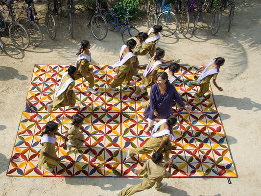Nani Marquina with children from the Amita School play with Kala rug