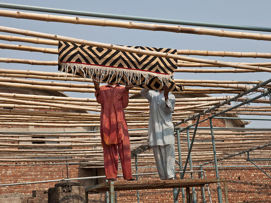 Artisans hanging Mélange rug on sticks